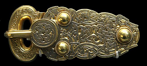 A heavy gold belt buckle, the loop and plate entirely covered in intricate interlaced animal-style ornament.