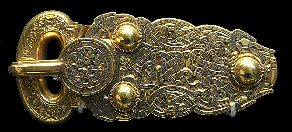 A heavy gold belt buckle, the loop and plate entirely covered in intricate interlaced animal-style ornament.