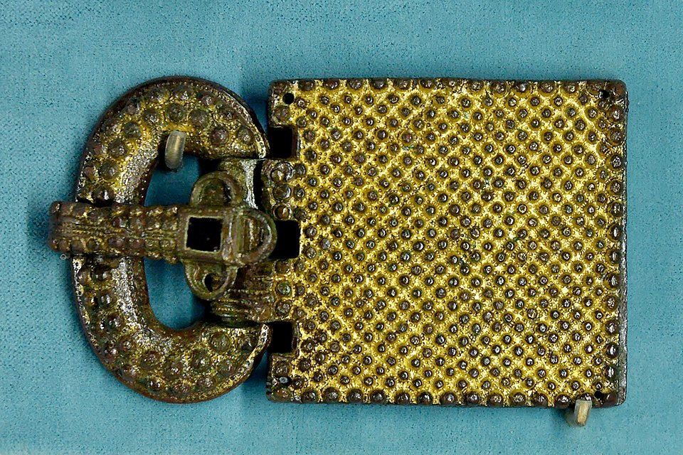 A rectangular Visigothic belt buckle with a metal frame and a large decorated plate inlaid with coloured stones and glass.